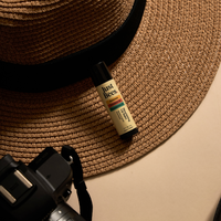 Just Bees lip balm styled with a travel hat and camera for an adventure theme